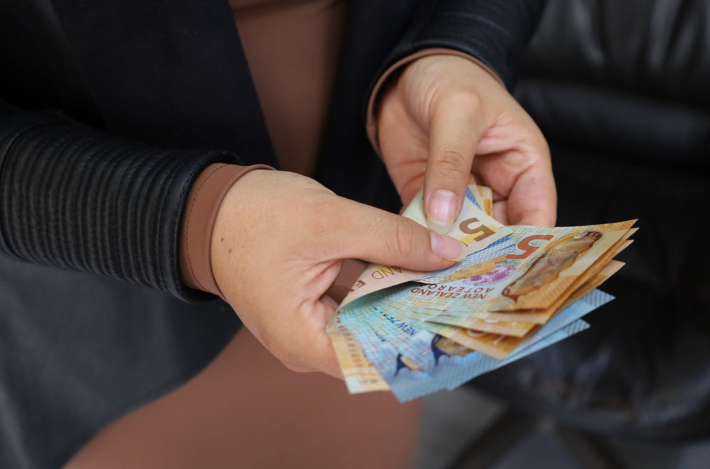 [New Zealand] The sectors barely paying above minimum wage - woman with handful of New Zealand banknotes, minimum wage New Zealand, low paying sectors New Zealand